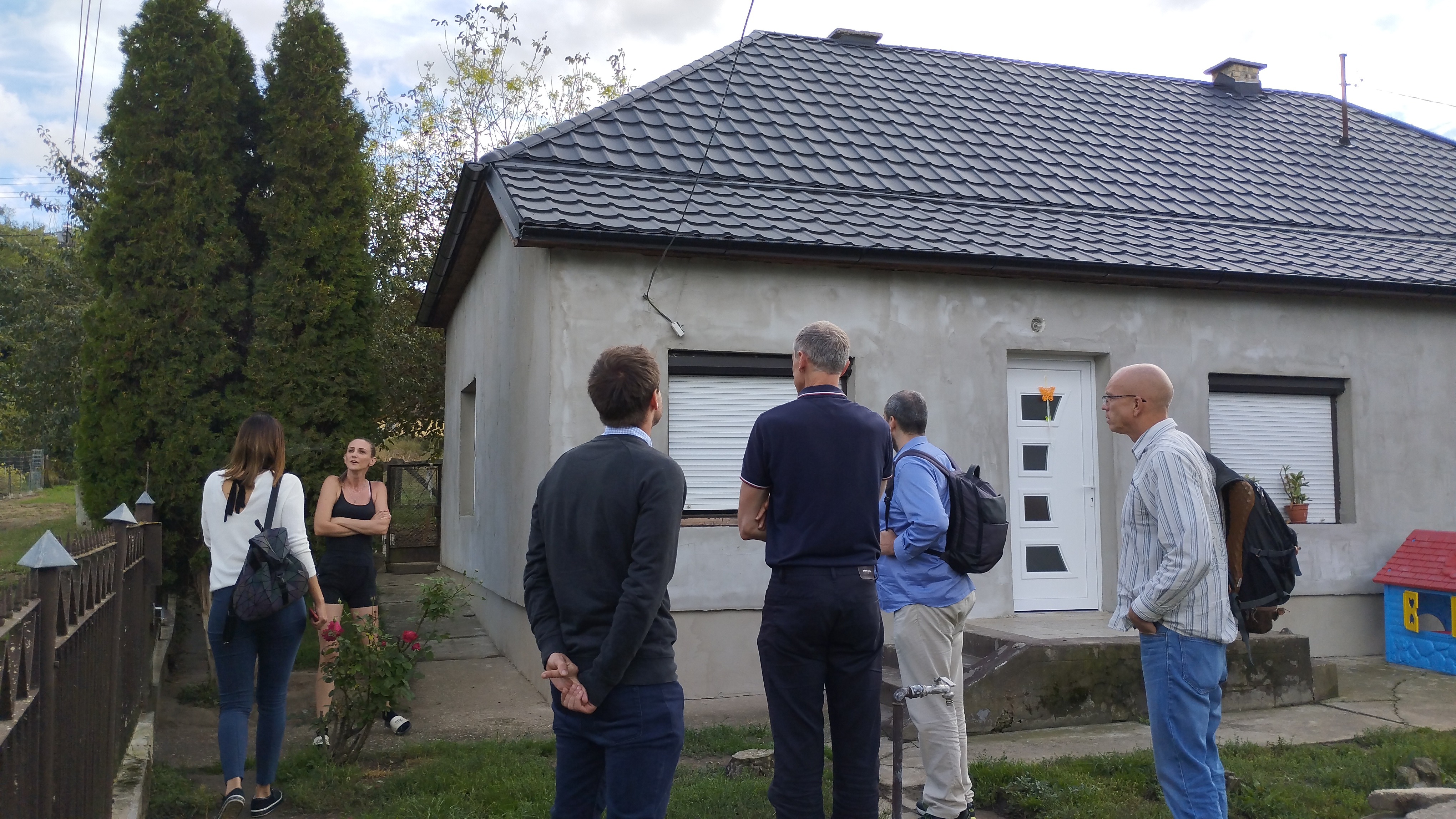 A photo of a group of people standing aorund a recently renovated house