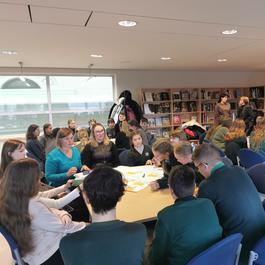 A photo of a group of young people / children engaging in shared work around a table. 