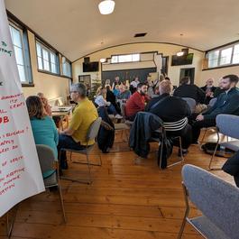 A photo showing a flipchart in the front and people in the background sitting around tables