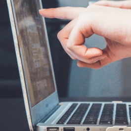 A photo of a hand pointing at a computer