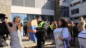 A police officer is using on a cardboard periscope to see out from further down with a childs perspective