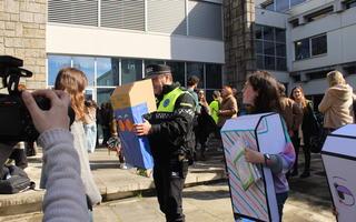 A police officer is using on a cardboard periscope to see out from further down with a childs perspective