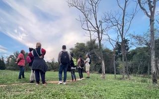 A group of people on a tour of their local area standing on a big grassy field.