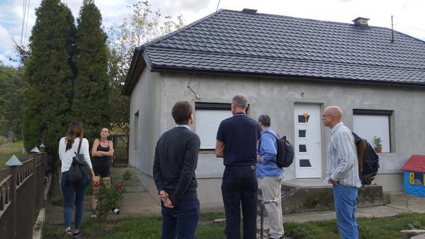 A photo of a group of people standing aorund a recently renovated house
