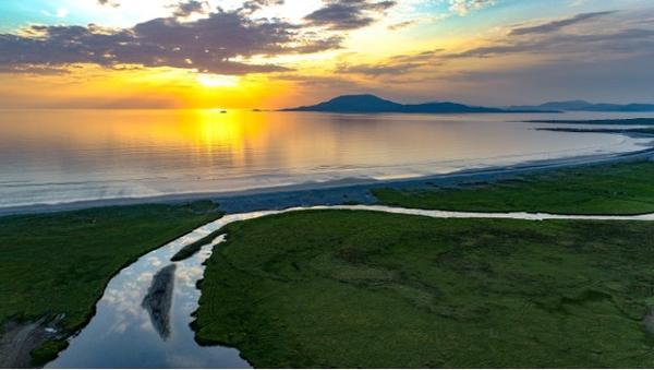 A green coastline with an island (clare Island) in the background