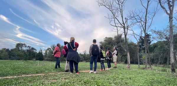 A group of people on a tour of their local area standing on a big grassy field.