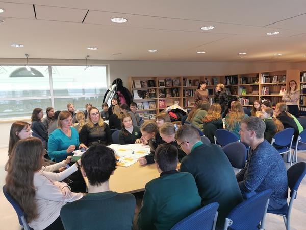 A photo of a group of young people / children engaging in shared work around a table.