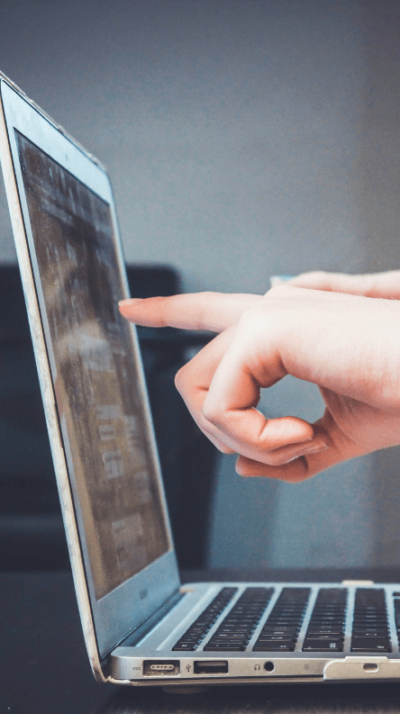 A photo of a hand pointing at a computer