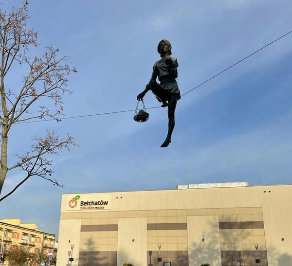 A statue of a young woman balancing a line high up in the air