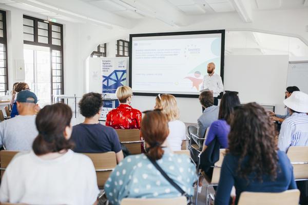 A group of people listening to a presentation in a brightly lit room