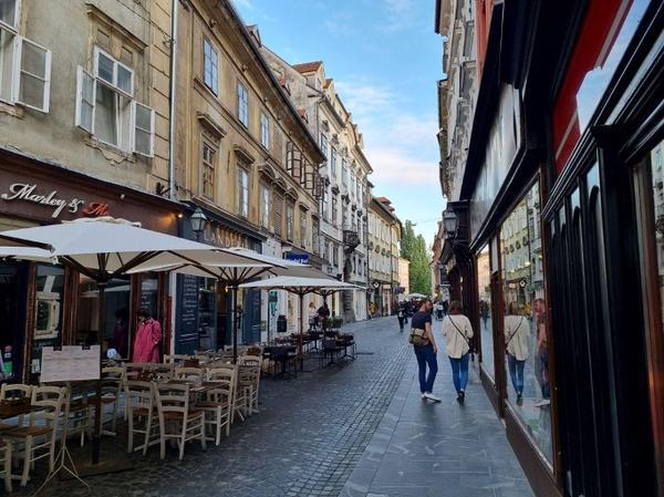 A small cozy and and walkable street. Some tables have been put out by a cafe.