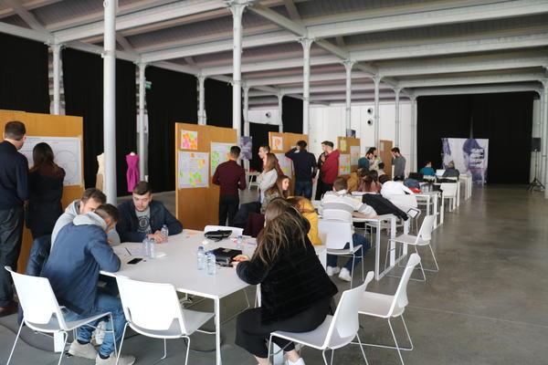 A group of people engaged in a from of brainstorming. Some sitting down others standing up. 